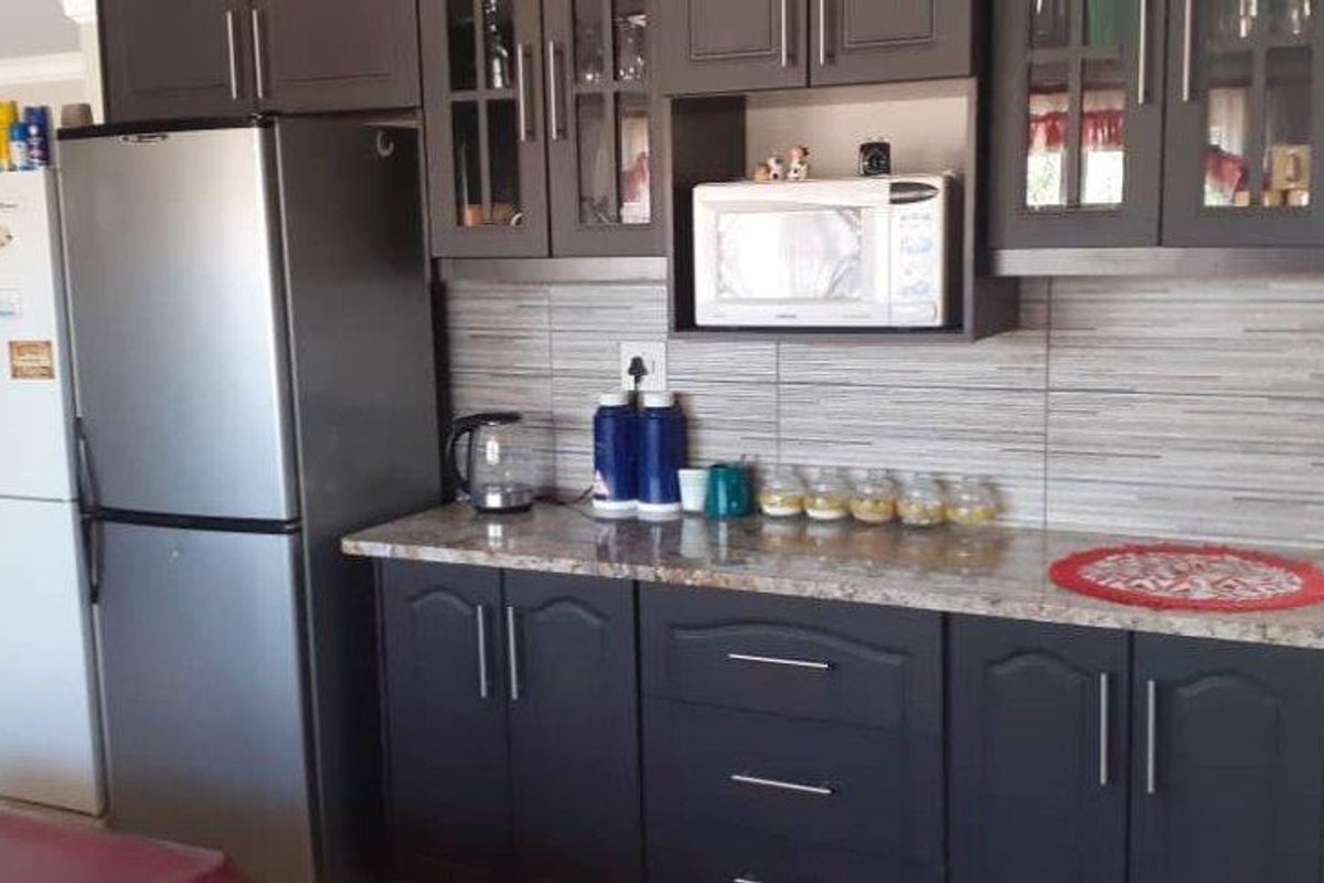 A functional kitchen area featuring dark cabinetry, granite-style countertops, and tiled backsplash, seamlessly integrated into the open-plan living space.
