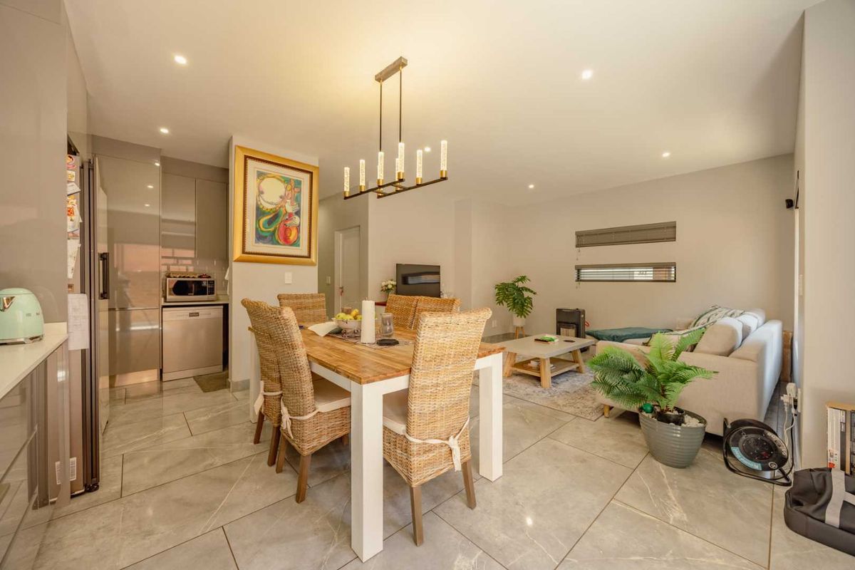 Modern open-plan living and dining area featuring sleek kitchen cabinetry, high-quality porcelain floor tiles, and contemporary recessed lighting throughout the space.