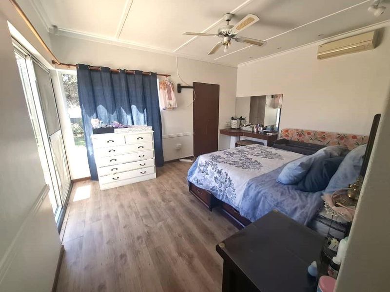 Spacious bedroom featuring laminate flooring, a ceiling fan, split-system air conditioning, and a sliding glass door providing access to the exterior.