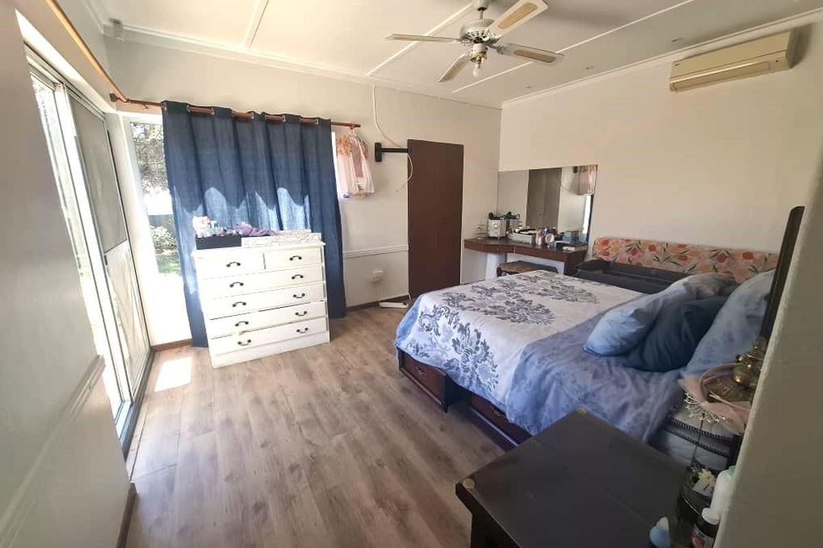 Spacious bedroom featuring laminate flooring, a ceiling fan, split-system air conditioning, and a sliding glass door providing access to the exterior.