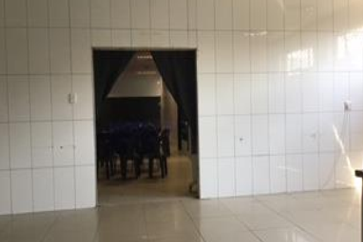 An interior space featuring fully tiled walls and flooring, with a doorway leading to an adjacent room.