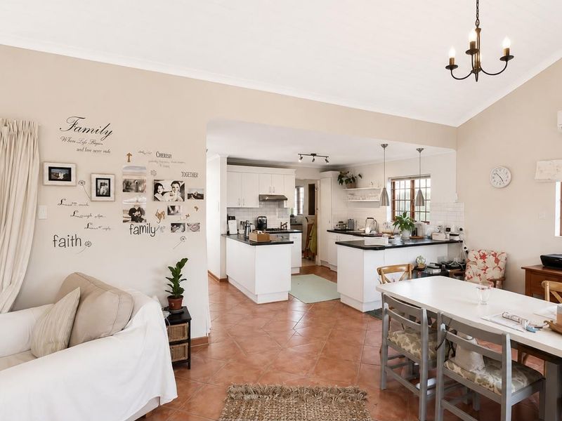 Spacious open-plan living, dining, and kitchen area featuring tiled floors, built-in cabinetry, and a split-system air conditioner, creating a functional and connected family space.