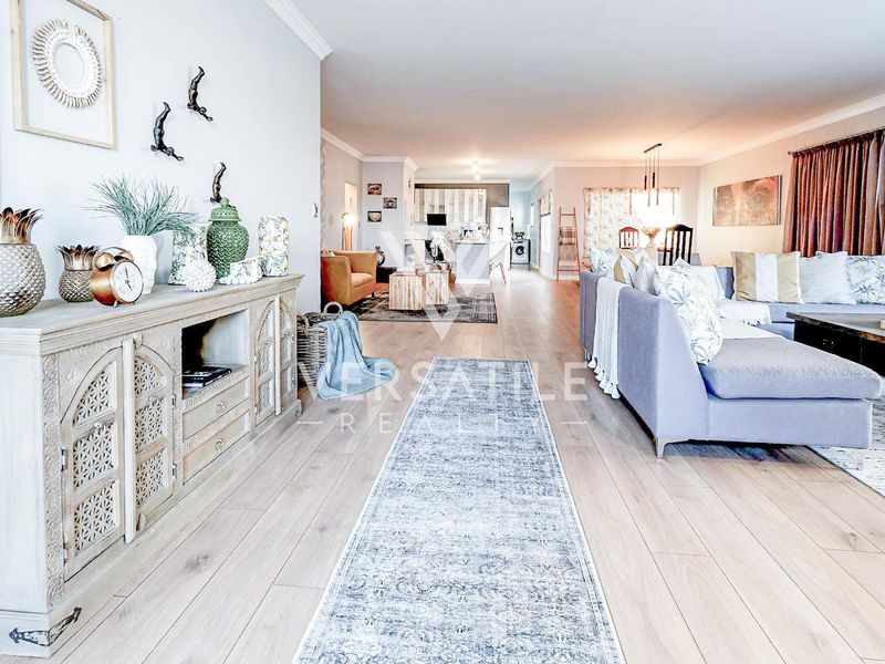 Spacious open-plan living area featuring light-toned laminate flooring, recessed lighting, and crown molding, seamlessly connecting the lounge, dining, and kitchen spaces.