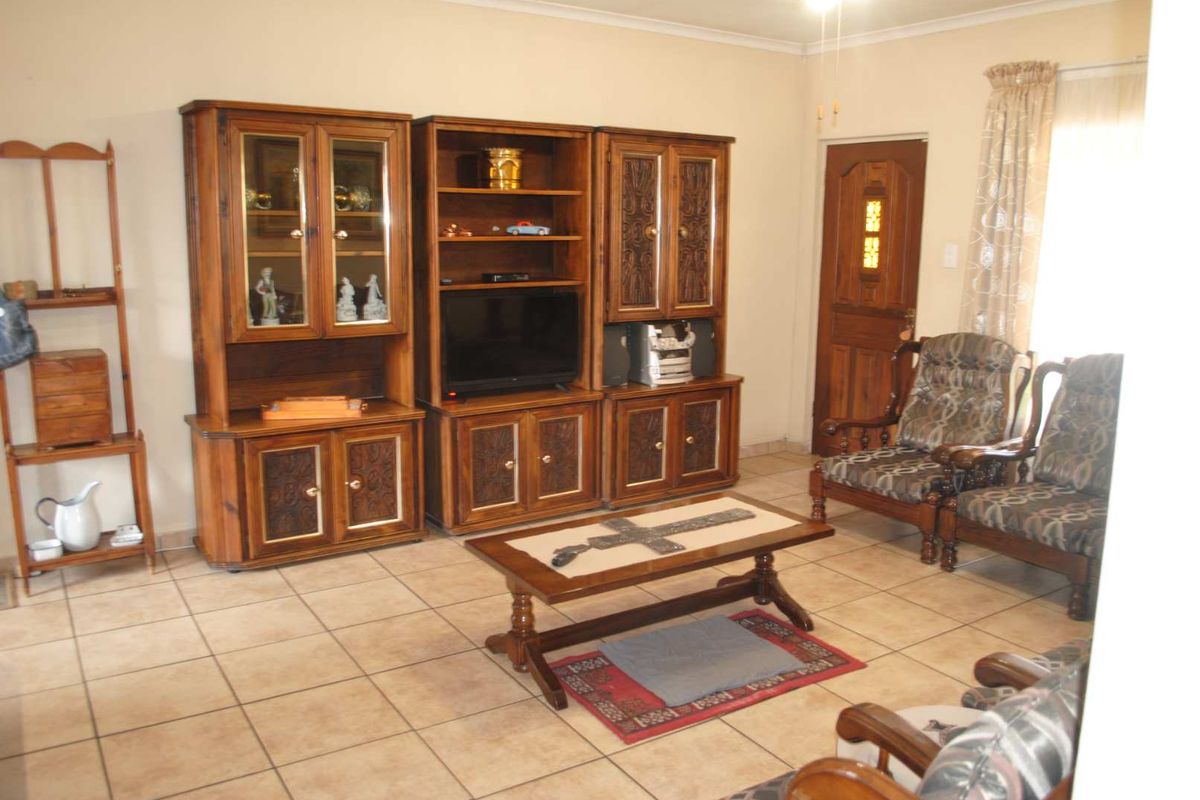 A living room featuring tiled flooring and a wooden door, offering a functional space with potential for modern updates.