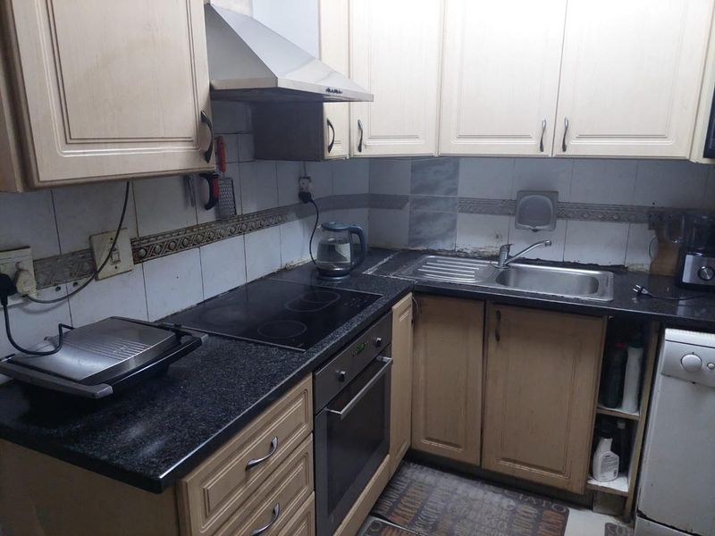 A functional kitchen featuring built-in cabinetry, granite countertops, a stainless steel sink, and integrated cooking appliances with a tiled backsplash.