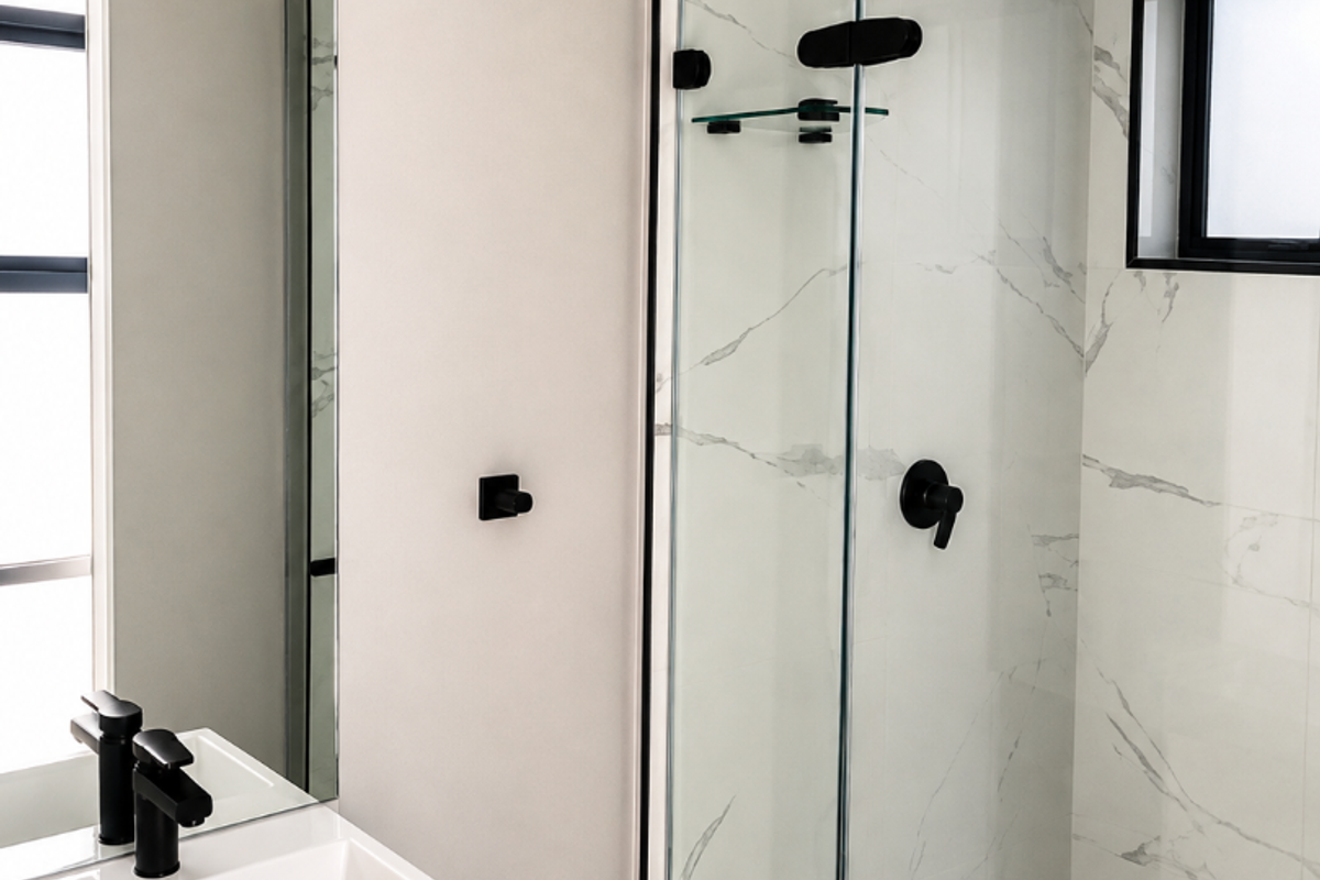 Modern bathroom featuring a sleek vanity with black fixtures, a walk-in shower with marble-look tiling, and contemporary black hardware throughout.