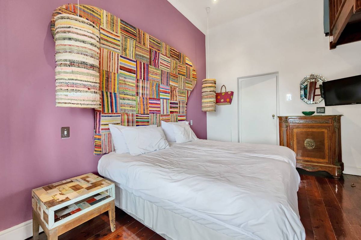 A well-maintained bedroom featuring polished hardwood flooring, recessed lighting, and a distinct purple accent wall.
