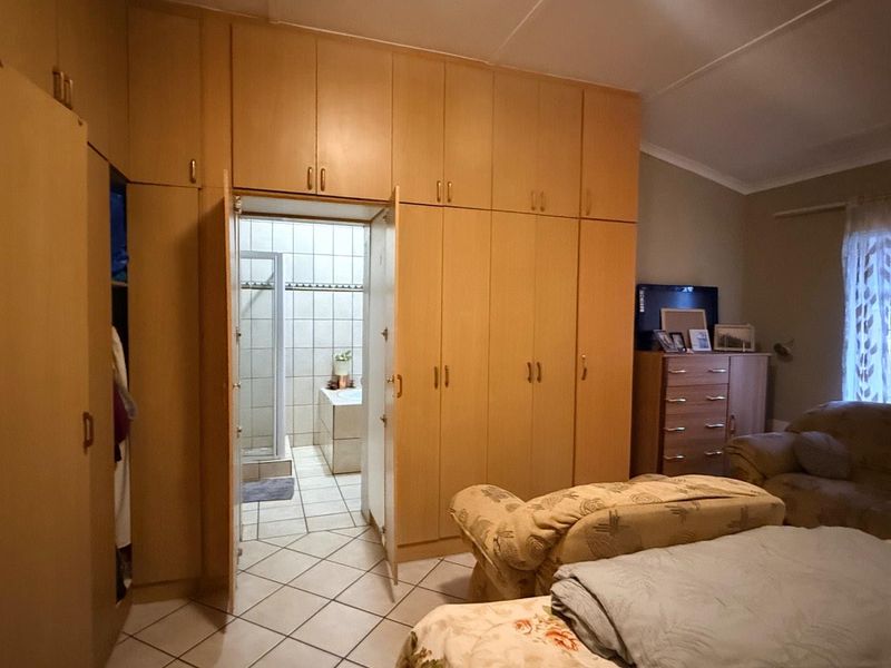 Bedroom featuring extensive floor-to-ceiling built-in cupboards, tiled flooring, and direct access to an en-suite bathroom.