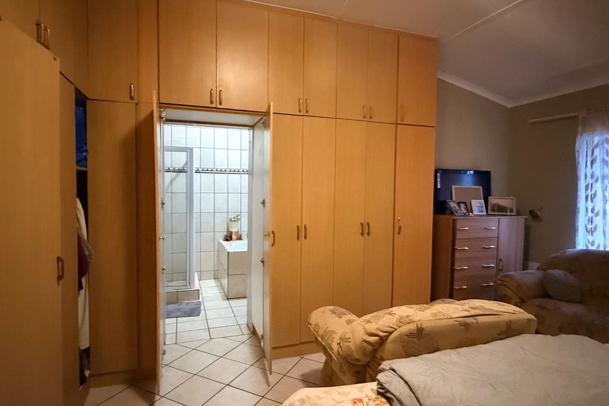 Bedroom featuring extensive floor-to-ceiling built-in cupboards, tiled flooring, and direct access to an en-suite bathroom.