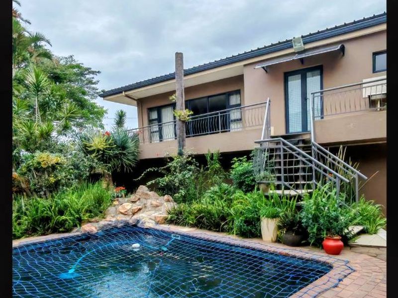 Outdoor pool area featuring brick paving, a metal staircase leading to an upper balcony, and established garden landscaping.