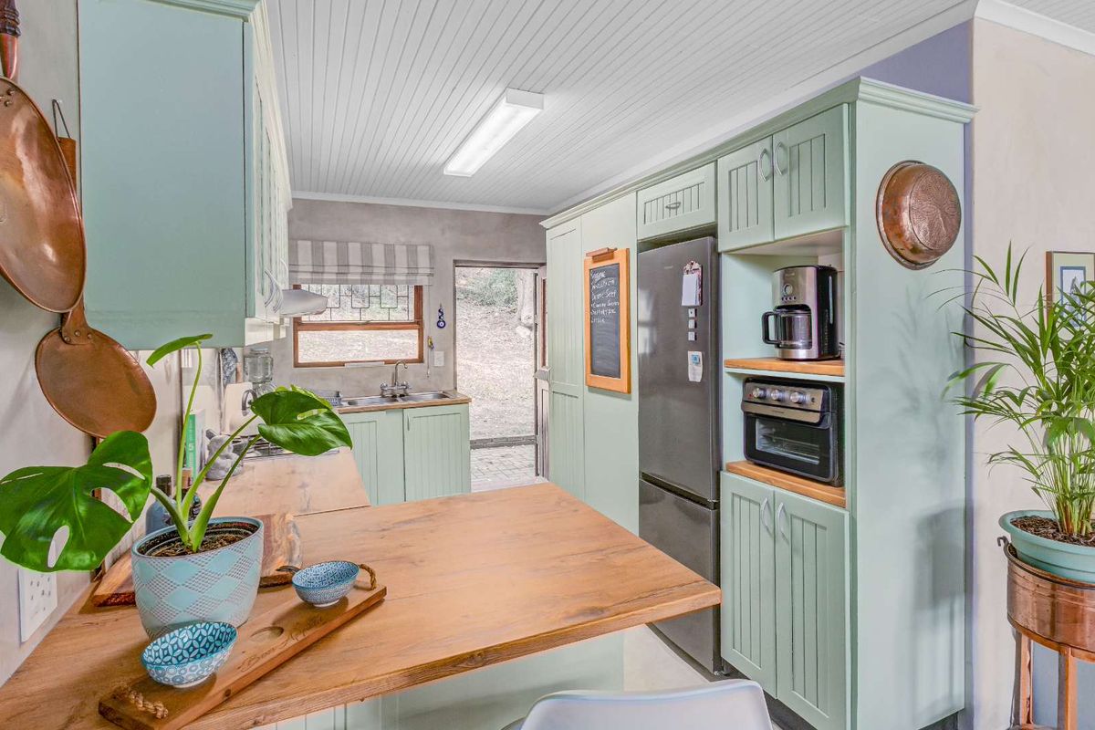 A charming kitchen featuring light green cabinetry, wooden countertops, a built-in oven, and direct access to the rear exterior.