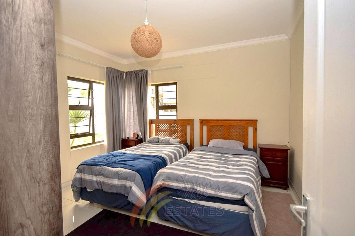 A well-lit bedroom featuring tiled flooring, corner windows, and crown molding, providing a comfortable and functional living space.
