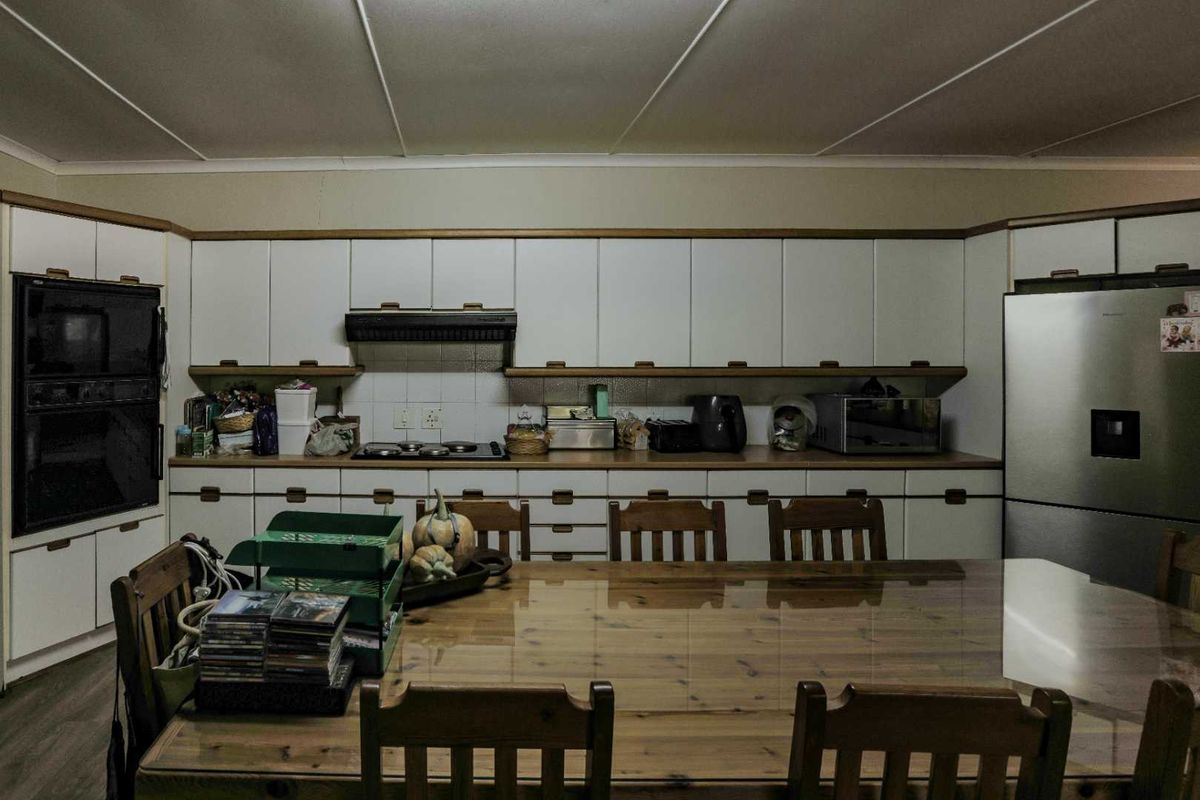A spacious kitchen featuring extensive white cabinetry, built-in oven, hob, and extractor fan, providing ample storage and workspace for meal preparation.