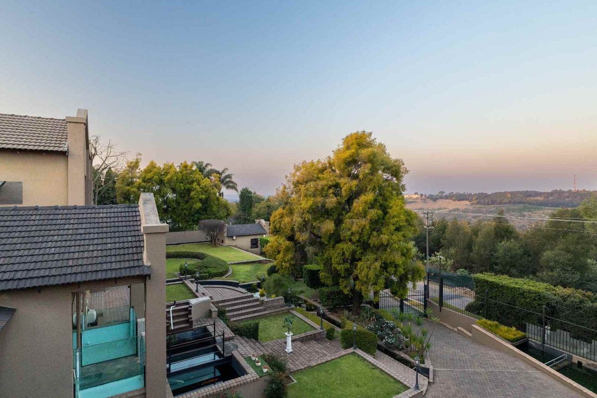 Elevated view of the rear property featuring a multi-level landscaped garden, paved driveway, and expansive scenic views.