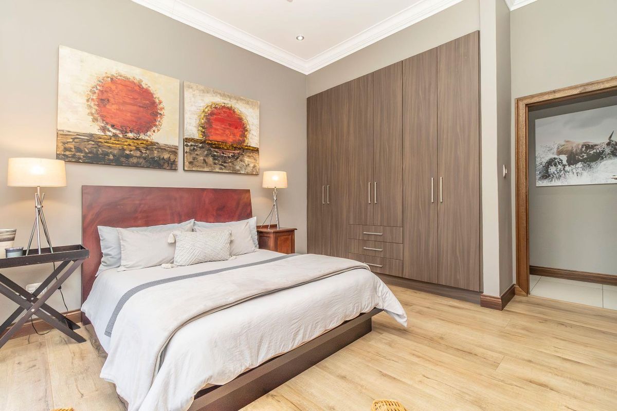 A well-maintained bedroom featuring modern laminate flooring, neutral wall tones, and extensive built-in cabinetry for storage.