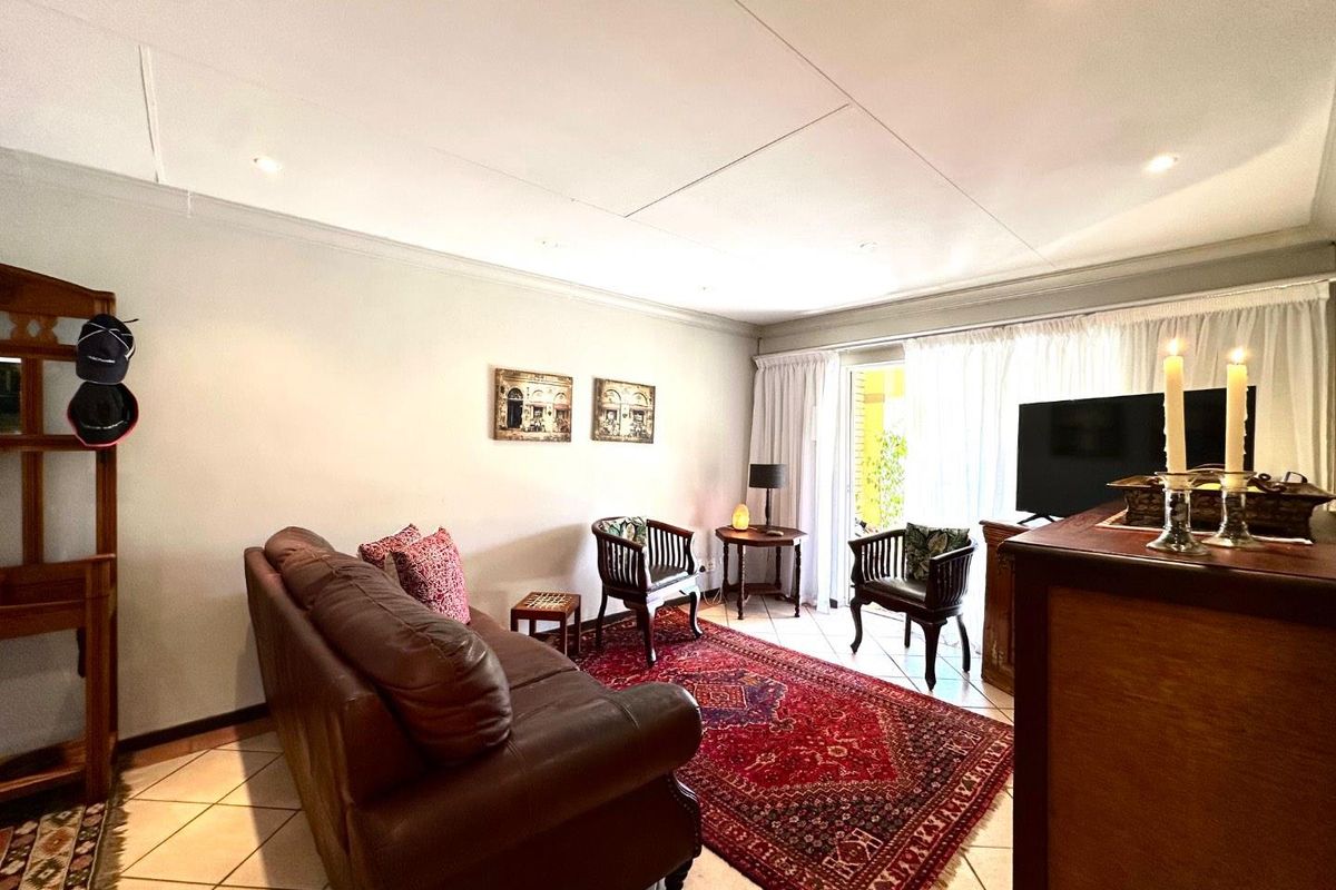 A comfortable living room featuring tiled flooring, recessed downlighting, and a sliding glass door providing access to the outdoor area.