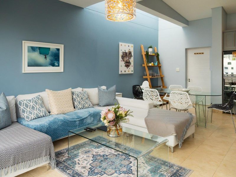 Bright open-plan living and dining area featuring high ceilings with a large skylight and neutral tiled flooring.