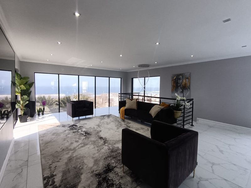 Spacious living area featuring large floor-to-ceiling windows with ocean views, modern marble-look tiled flooring, and recessed downlighting.