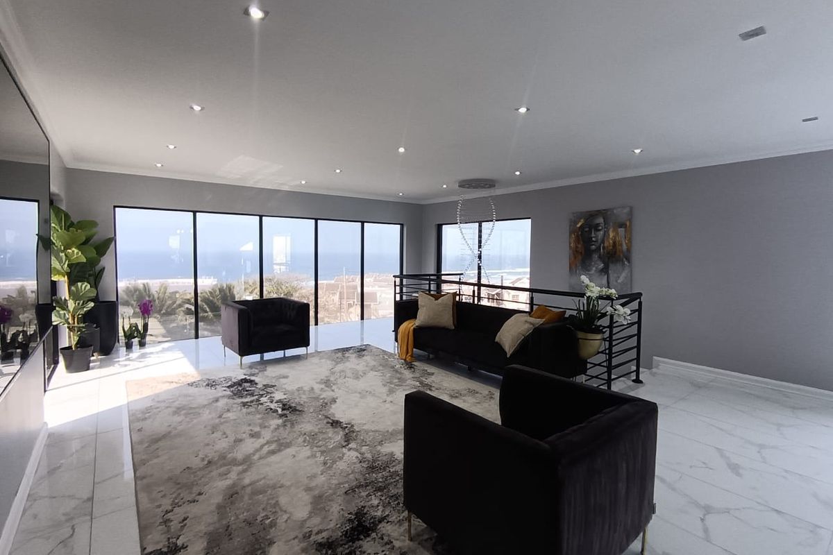 Spacious living area featuring large floor-to-ceiling windows with ocean views, modern marble-look tiled flooring, and recessed downlighting.