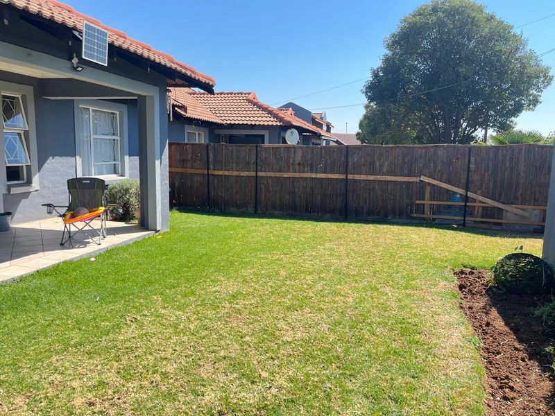 A private rear garden featuring a tiled patio area, a well-maintained lawn, and perimeter wooden fencing.