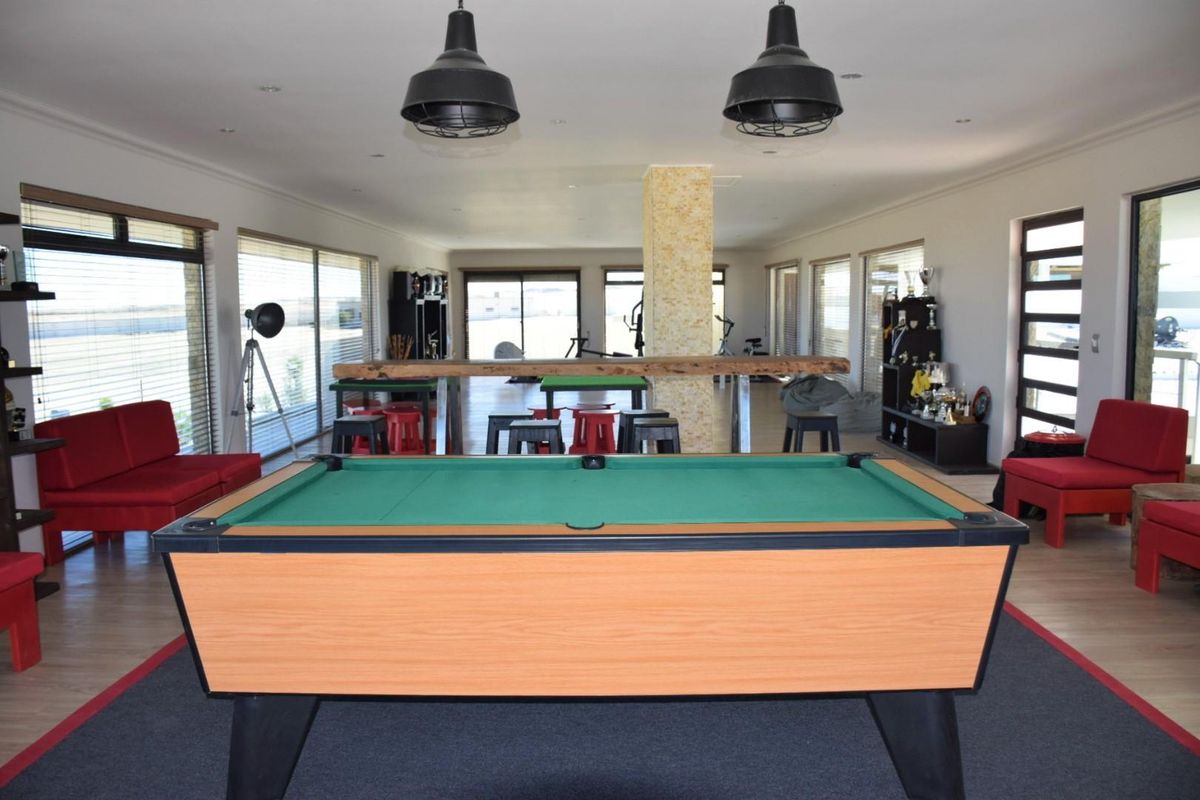 Spacious entertainment area featuring large windows, recessed lighting, and a central stone-clad pillar, ideal for a games room or recreational space.