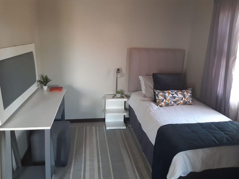 A compact bedroom featuring neutral wall finishes and a window with curtaining.