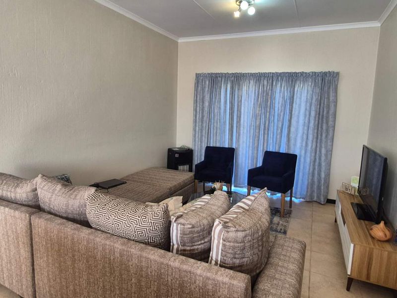 A comfortable living room featuring tiled flooring and a sliding glass door that provides natural light.
