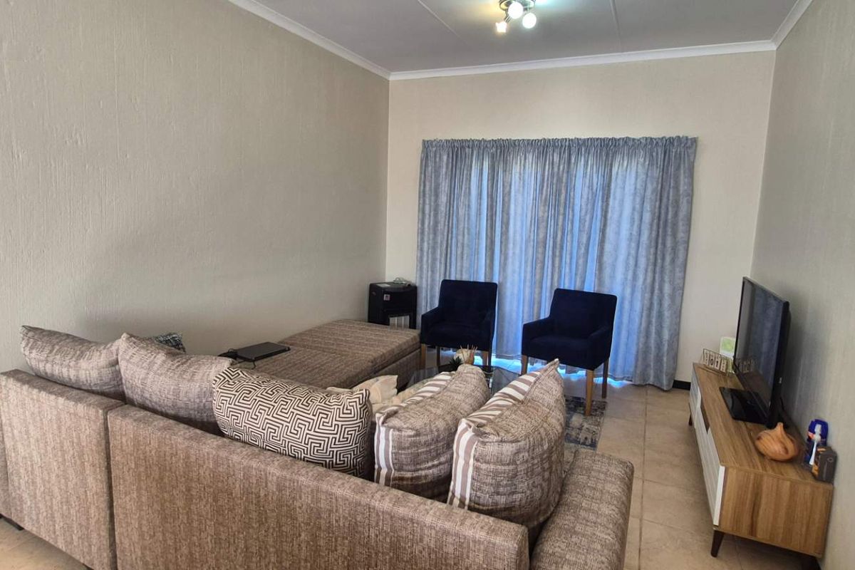 A comfortable living room featuring tiled flooring and a sliding glass door that provides natural light.