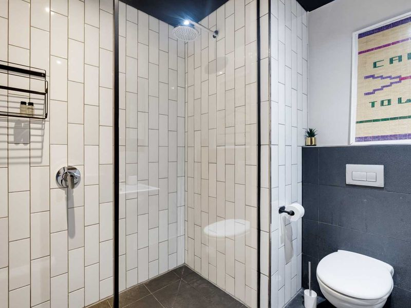 Modern bathroom featuring a walk-in shower with a rain shower head, subway tiling, and a wall-mounted toilet with a concealed cistern.