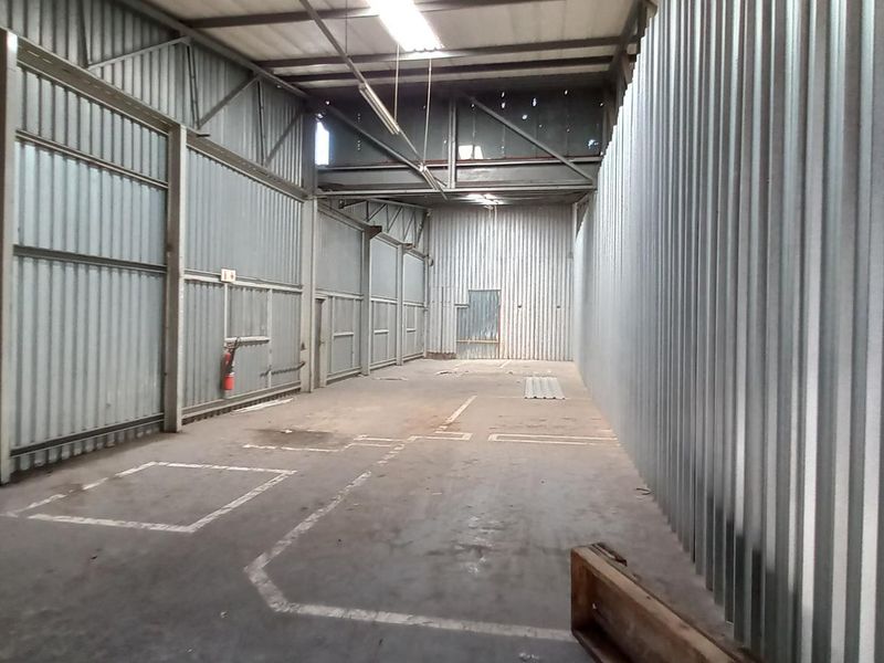 Spacious industrial utility area featuring corrugated metal walls, exposed steel roof structure, and durable concrete flooring, suitable for storage or workshop use.