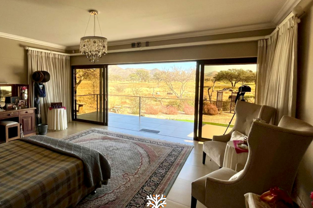 Spacious bedroom featuring large sliding glass doors that open onto a private balcony with scenic landscape views.