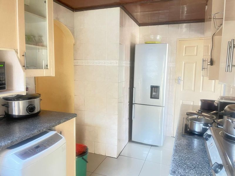 A functional kitchen featuring tiled walls, laminate countertops, and built-in cabinetry, offering a practical layout with integrated cooking appliances.