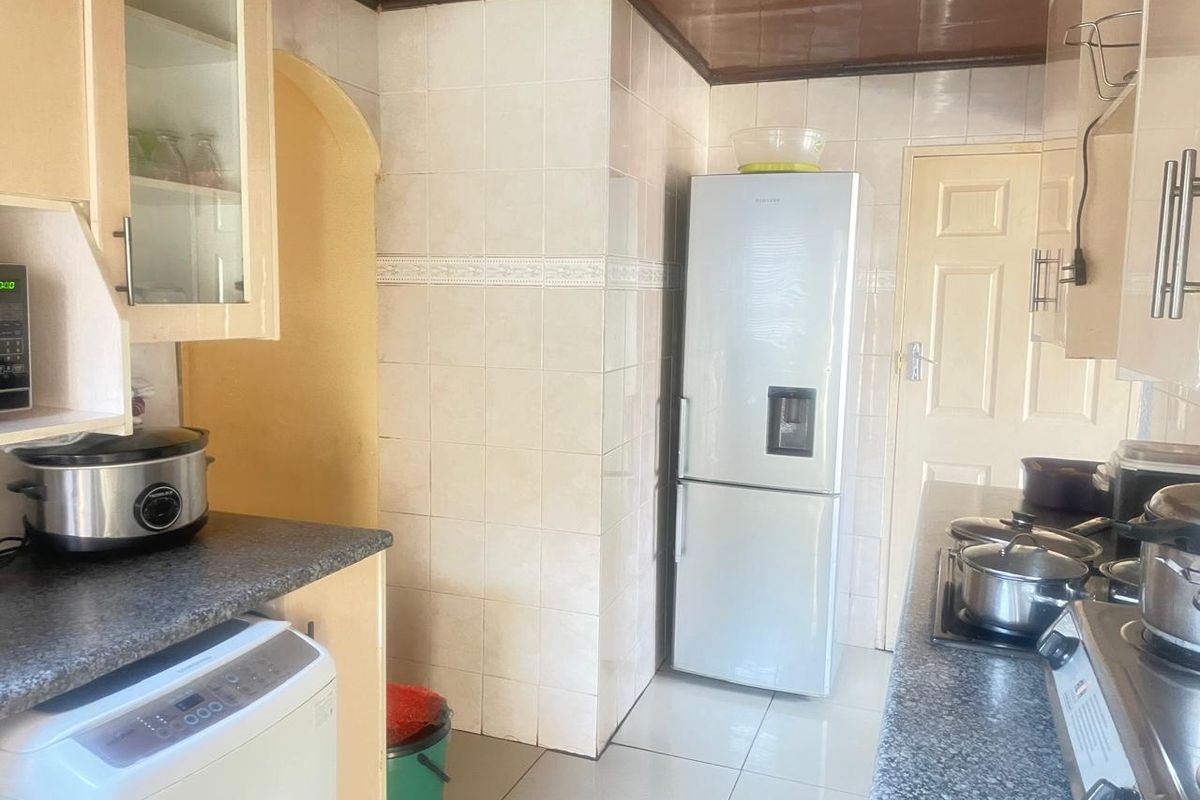 A functional kitchen featuring tiled walls, laminate countertops, and built-in cabinetry, offering a practical layout with integrated cooking appliances.