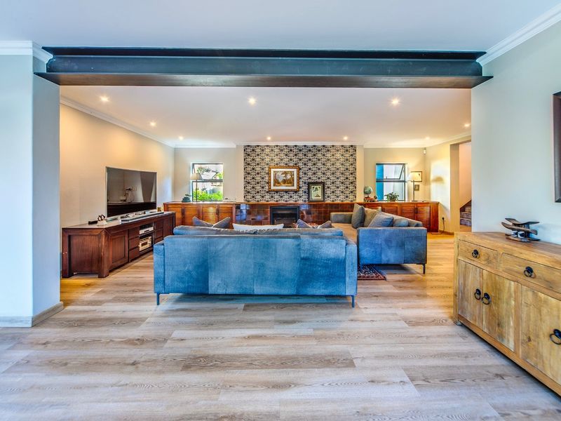 Spacious living room featuring a prominent exposed steel beam, modern laminate flooring, built-in cabinetry, and a decorative tiled fireplace feature wall.