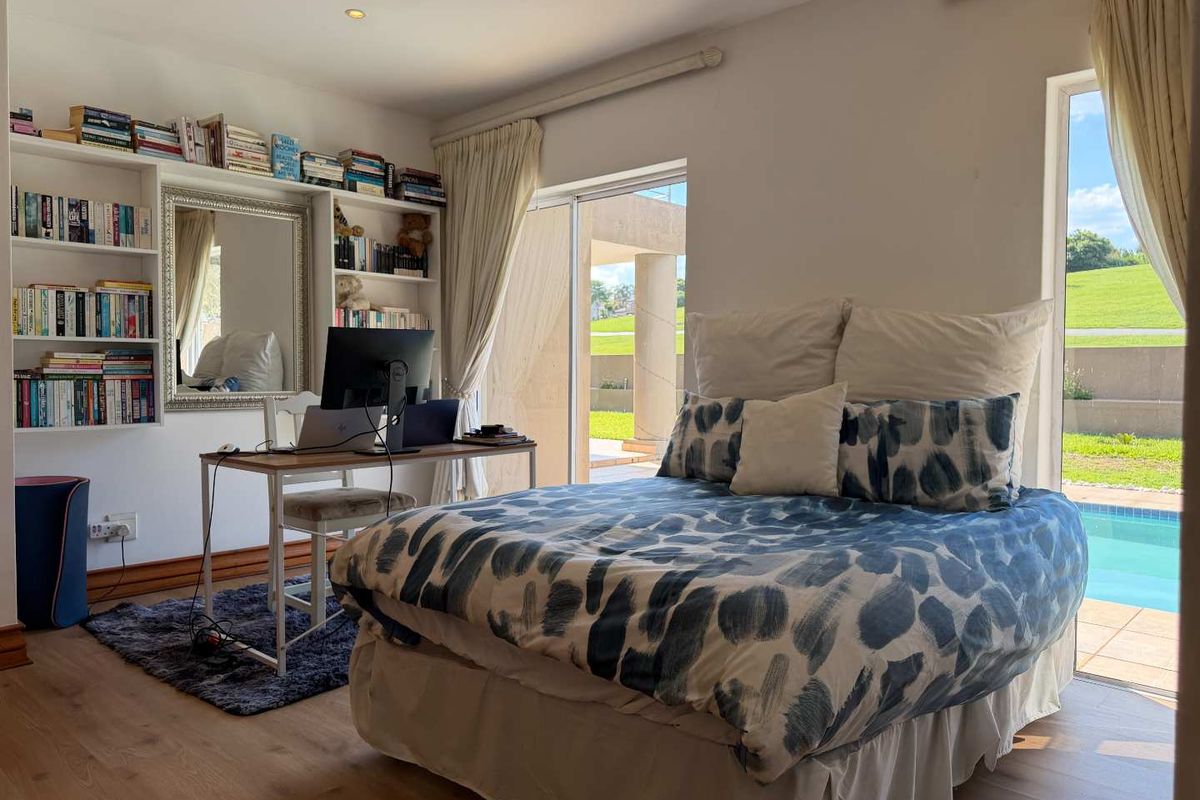 A bright bedroom featuring laminate flooring, built-in shelving, and sliding glass doors that provide direct access to the patio and pool area.