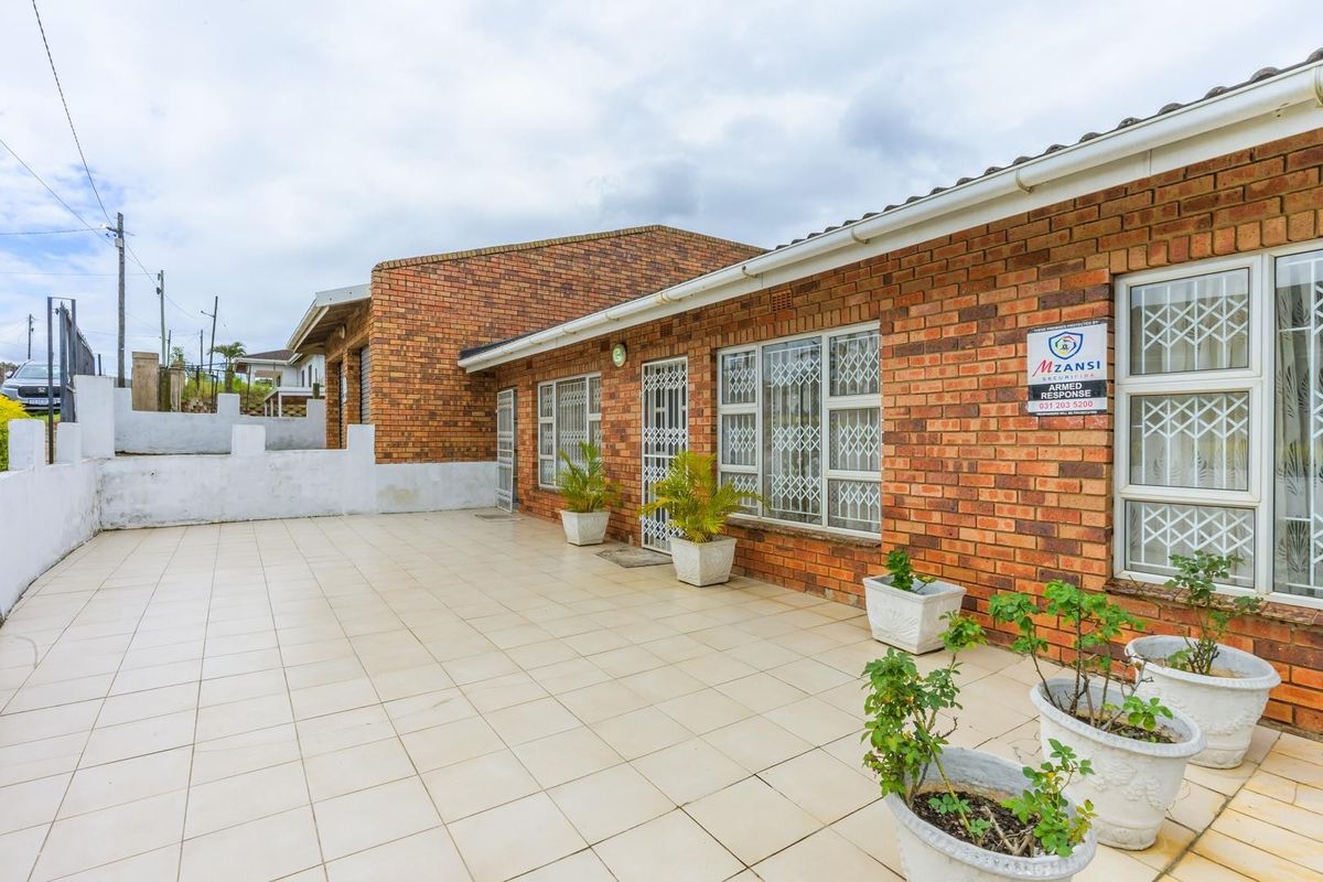 A spacious rear patio area featuring face brick exterior walls, tiled flooring, and secure window and door fittings.