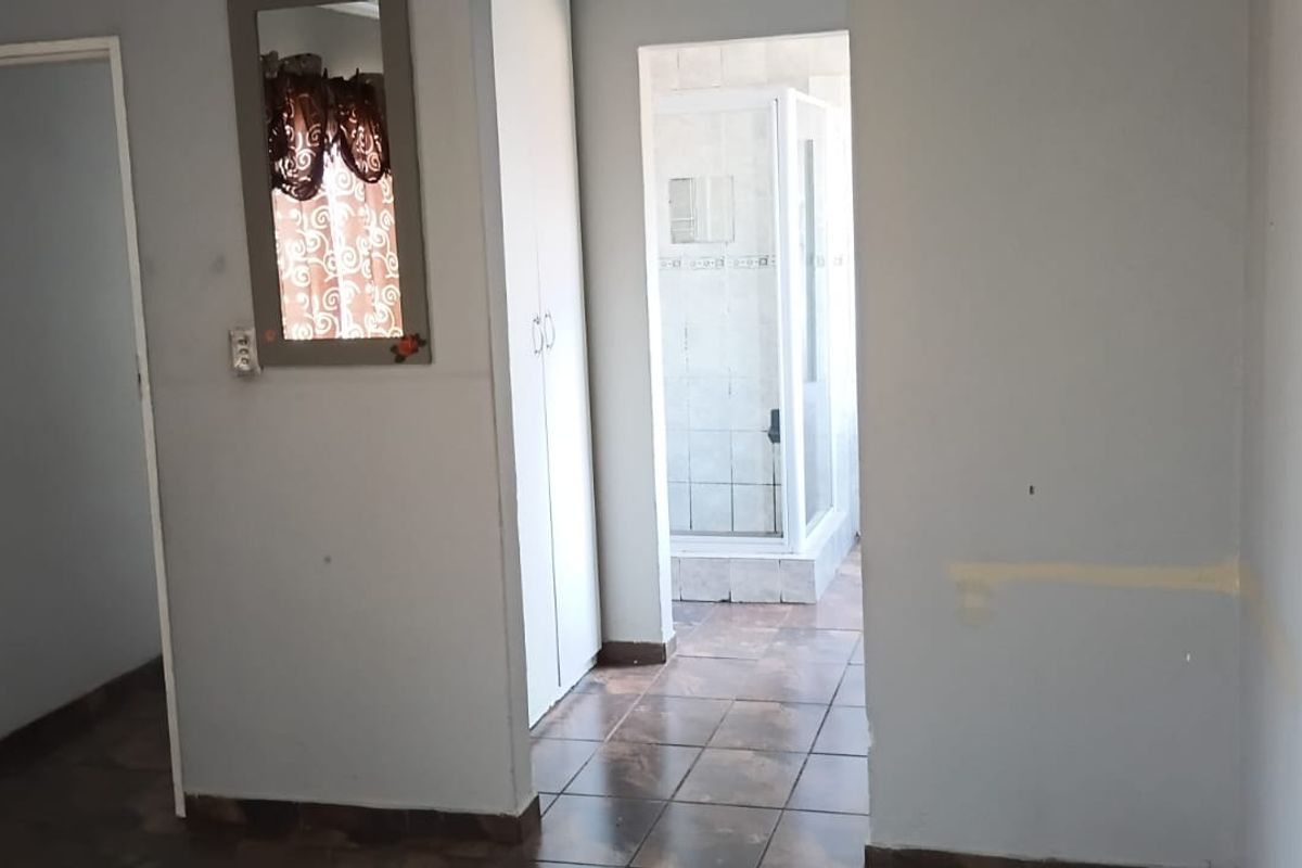 A vacant bedroom featuring tiled flooring, a built-in cupboard, and direct access to an en-suite bathroom.