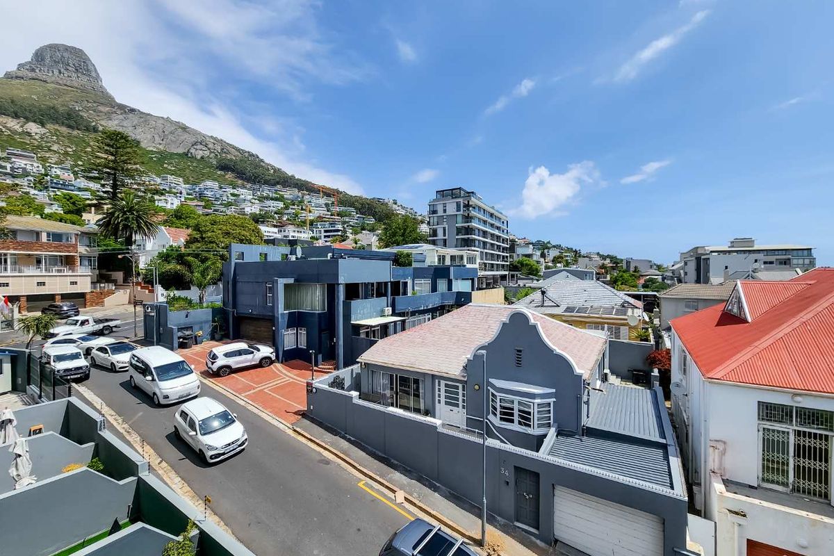 An elevated aerial view of the residential street and surrounding neighborhood, showcasing the property's location and proximity to local infrastructure and mountain scenery.