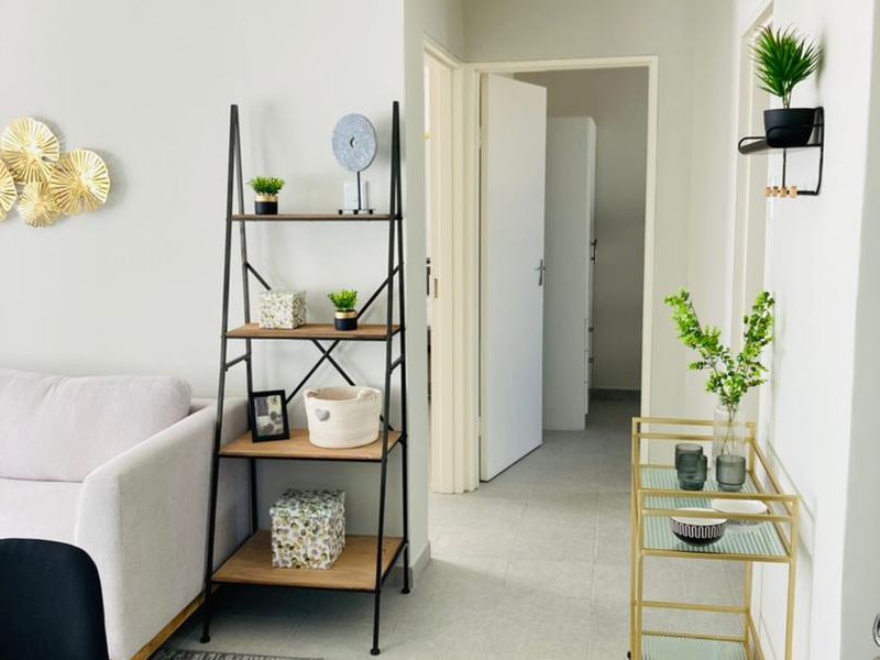 A bright, neutral-toned hallway featuring tiled flooring and access to adjacent rooms, providing a clean and functional transition space within the apartment.