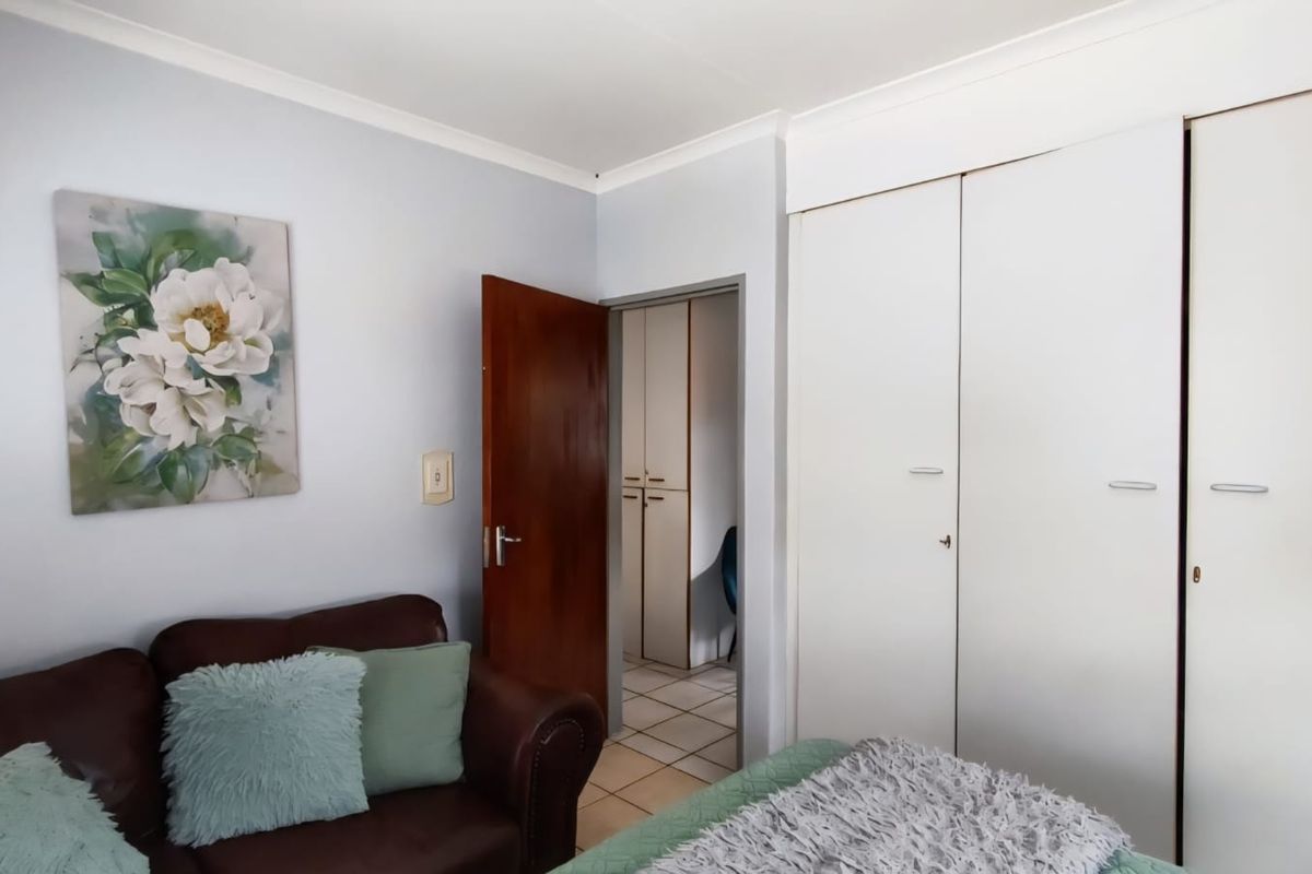 A bedroom featuring built-in cupboards, coved ceilings, and a doorway leading to an adjacent tiled hallway with additional storage.