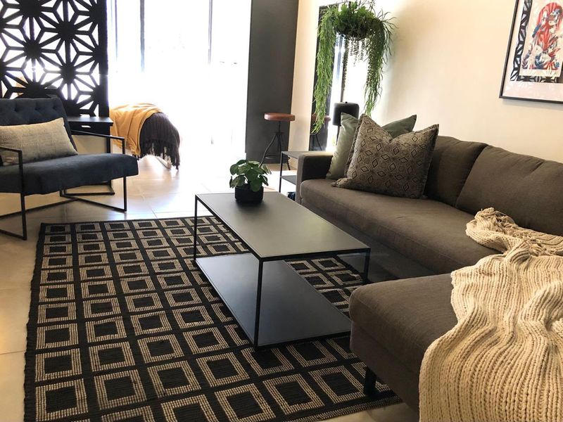 A modern, well-lit living room featuring neutral tiled flooring and a decorative geometric room divider, creating a stylish and contemporary open-plan feel.