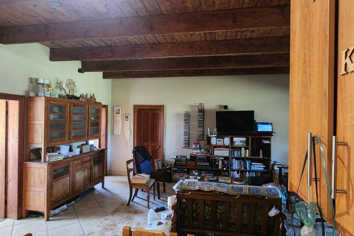 A living area featuring rustic exposed timber ceiling beams, tiled flooring, and solid wood doors, offering a traditional farm-style aesthetic.