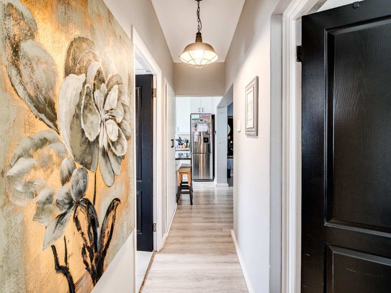 A well-lit hallway featuring modern laminate flooring and dark-finished internal doors, providing a clean transition between living spaces.