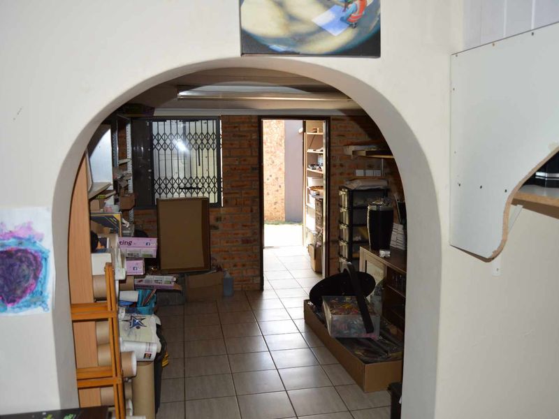 A utility space featuring exposed brick walls, tiled flooring, and an arched entrance, providing functional storage or workspace potential.