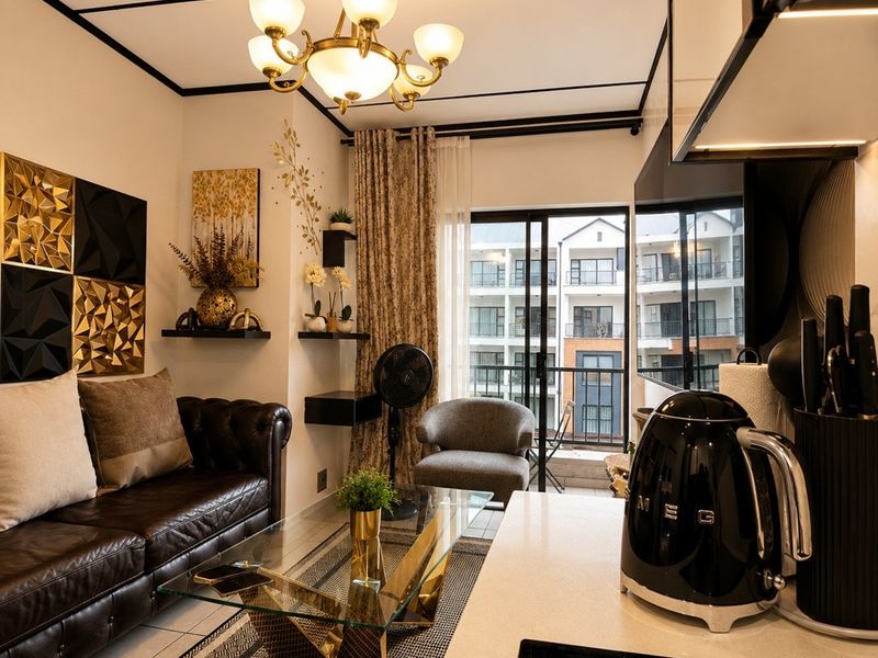 Modern open-plan living area featuring a sleek kitchen with stone countertops, induction hob, and direct access to a private balcony through sliding glass doors.