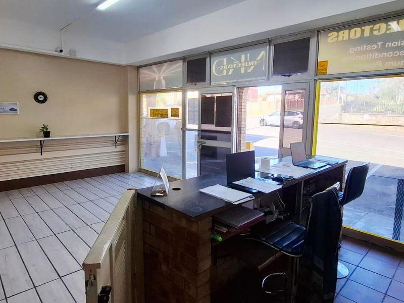 Commercial office space featuring a built-in brick reception counter, large street-facing glass windows, and tiled flooring, suitable for a retail or service-based business.