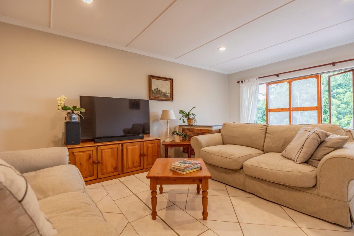 A comfortable living room featuring tiled flooring, recessed ceiling lighting, and large windows that provide natural light.