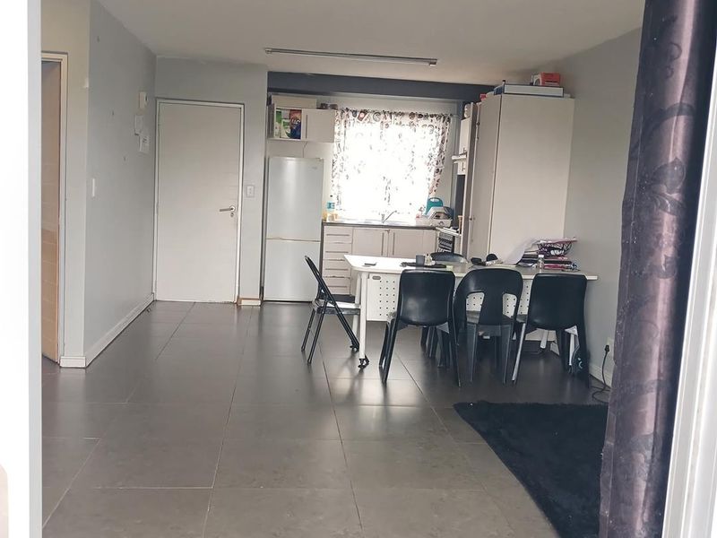Open-plan living and kitchen area featuring large format floor tiles and functional built-in cabinetry, offering a versatile space for dining and relaxation.