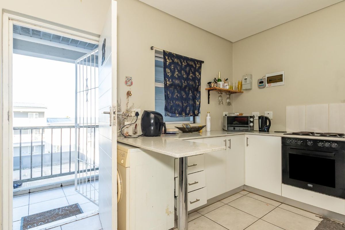Compact kitchen featuring white cabinetry, stone countertops, built-in oven and hob, with direct access to a private balcony.