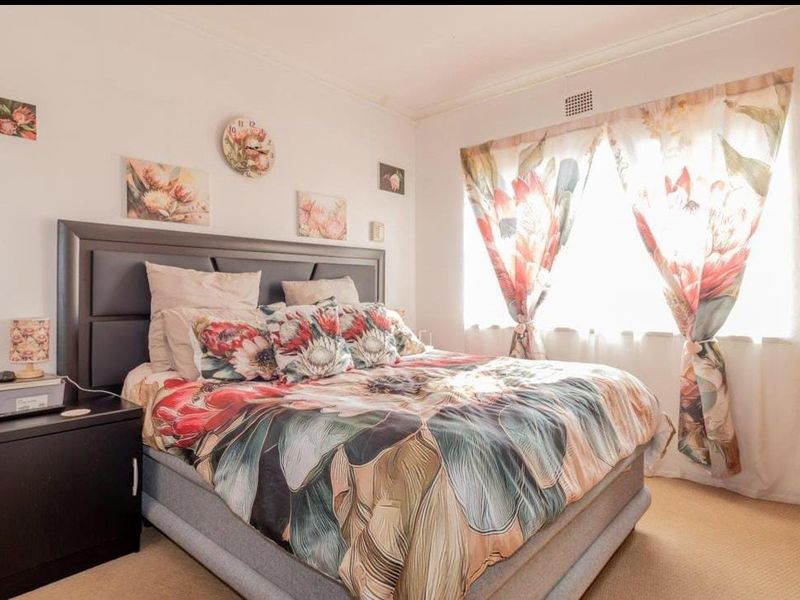 A well-lit bedroom featuring neutral wall finishes, carpeted flooring, and a built-in ventilation system.